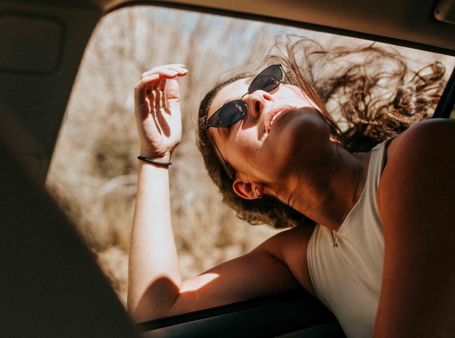 woman in white tank top wearing sunglasses sitting inside car